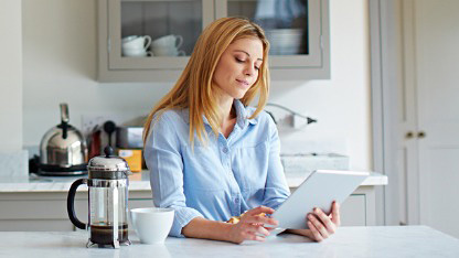 Woman in kitchen reading tablet Woman in kitchen reading tablet
